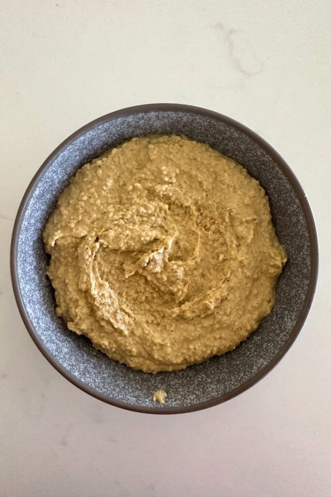 A grey stoneware bowl filled with a hummus recipe made without tahini.