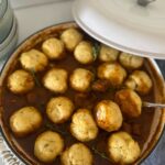 A large white enamel pot filled with sourdough Irish stew and topped with sourdough herbed dumplings.