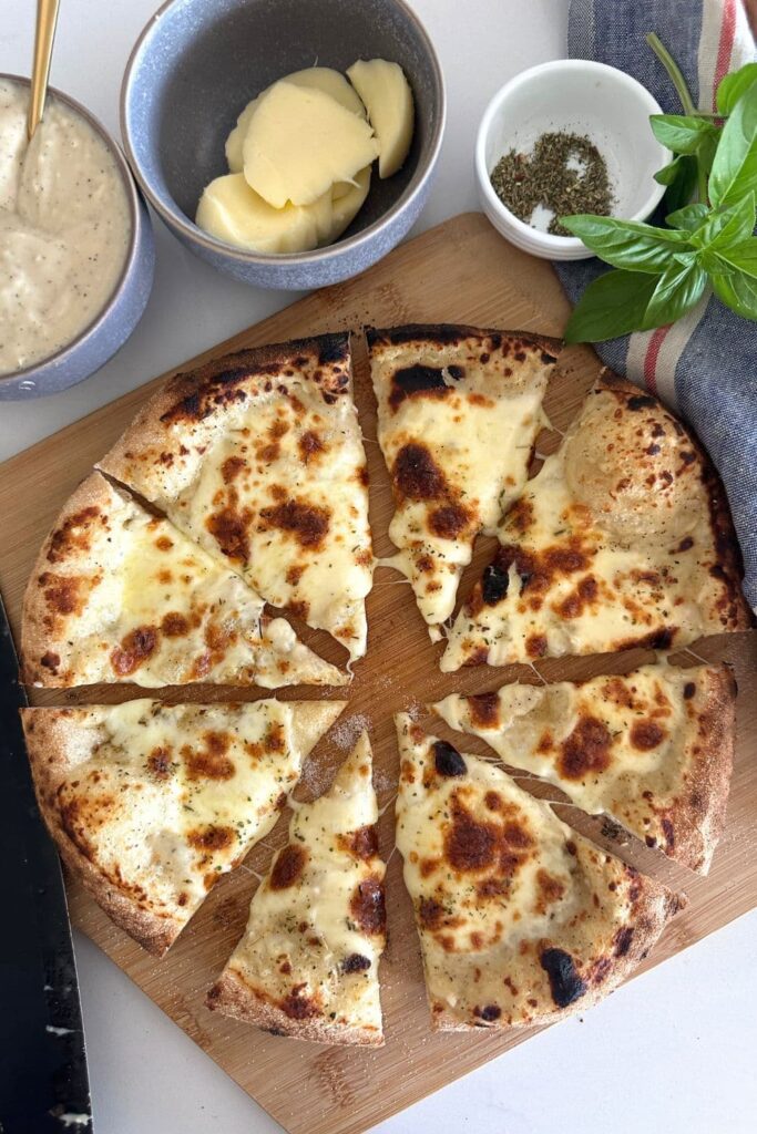 A sourdough pizza base topped with white pizza sauce and mozzarella cheese.