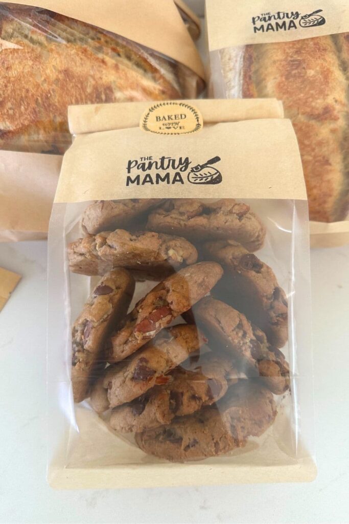 Sourdough chocolate chip cookies pacakged in a clear plastic bag with a brown paper top.