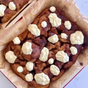 A tray of sourdough cinnamon roll focaccia bread topped with gooey vanilla cream cheese frosting.