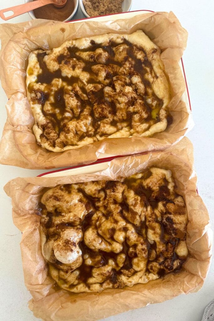 Sourdough cinnamon roll focaccia bread topped with melted butter, brown sugar and cinnamon. The dough has been dimpled to spread the topping through the dough.