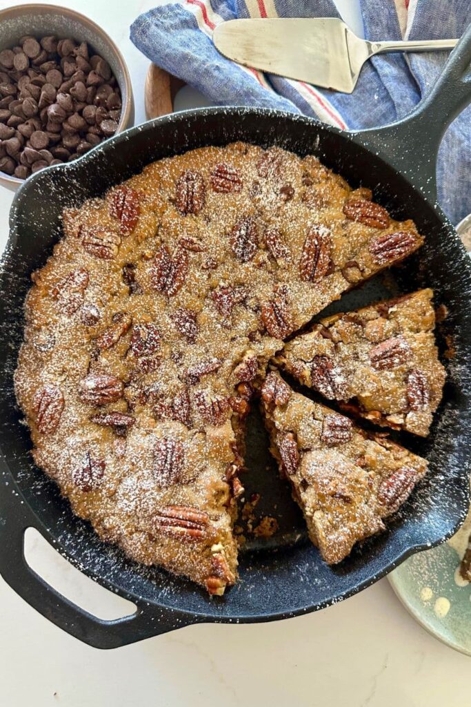 A spiced pecan chocolate chip sourdough cookie skillet dusted with icing sugar. 