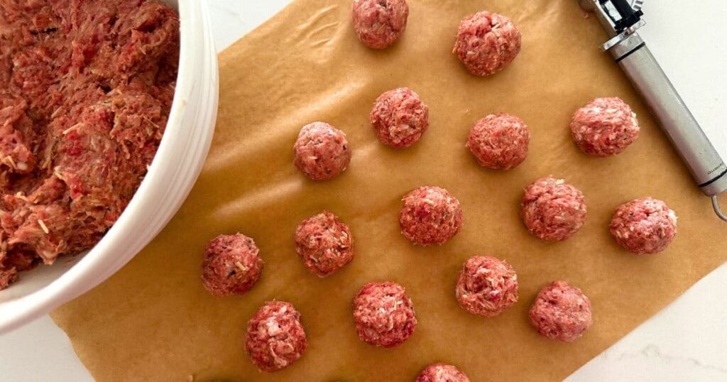 Sourdough meatballs laid out on a slice of parchment paper. 