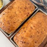 2 loaves of golden sourdough cheese bread sitting in 1.5 pound USA loaf pans.