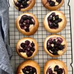Sourdough blueberry brioche tarts with a cheesecake filling sitting on a black wire rack as a delicious sourdough discard dessert.