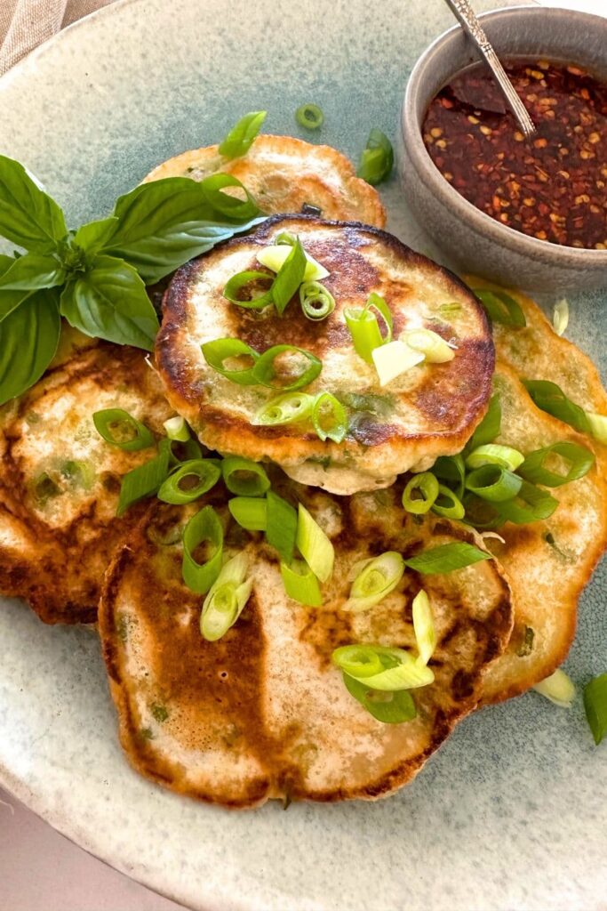 A plate of sourdough discard scallion pancakes topped spring onions and served with chilli soy dipping sauce.