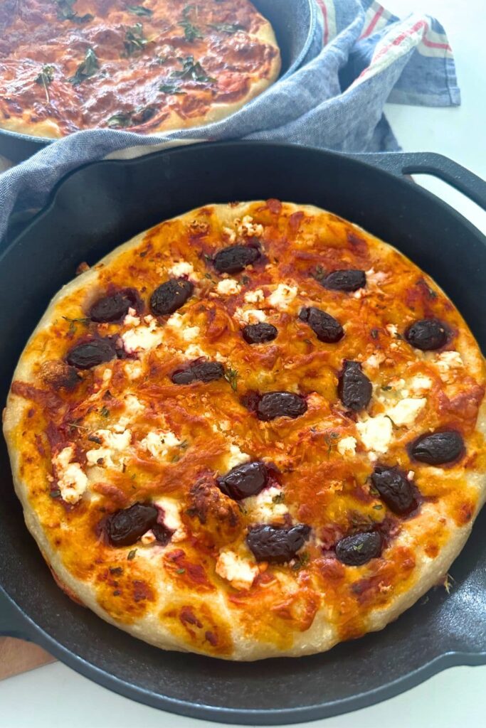 Sourdough pizza focaccia bread topped with feta and olives and baked in a cast iron skillet.