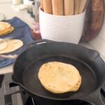 Cast iron skillet being used to cook sourdough discard flat bread.