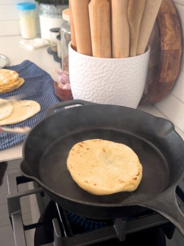 Cast iron skillet being used to cook sourdough discard flat bread.