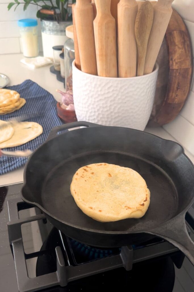 Cast iron skillet being used to cook sourdough discard flat bread. 