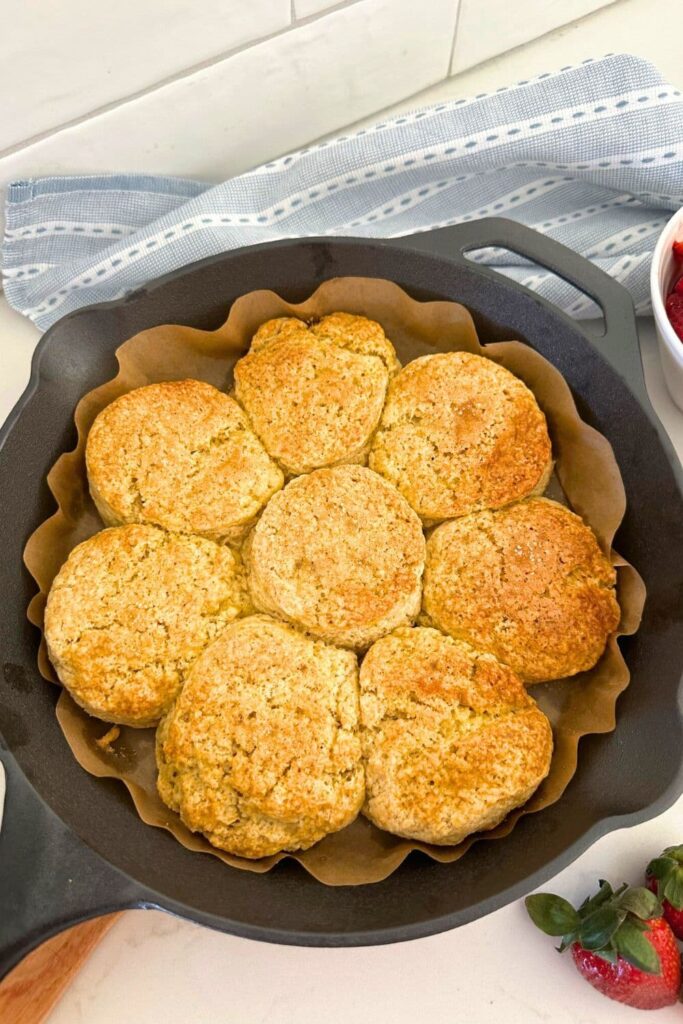 A cast iron skillet filled with sourdough biscuits topped with granular sugar.