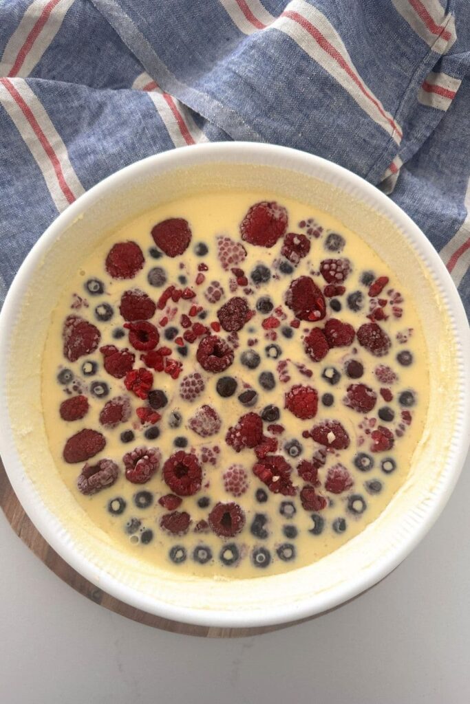 A sourdough clafoutis topped with colorful berries. It is about to be baked in the oven.