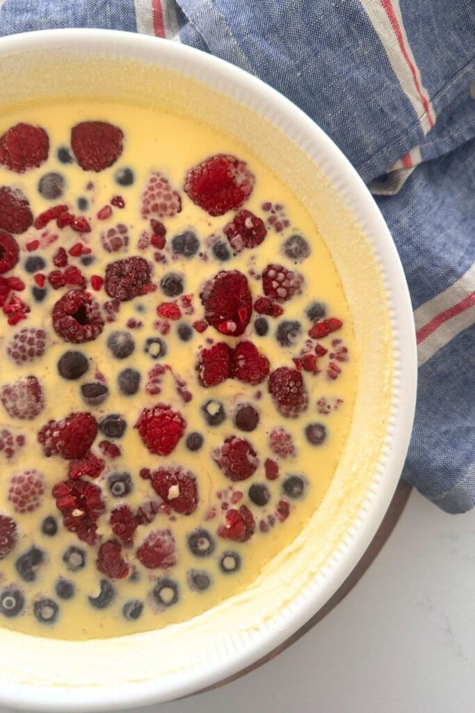 A sourdough clafoutis topped with colorful berries. It is about to be baked in the oven.