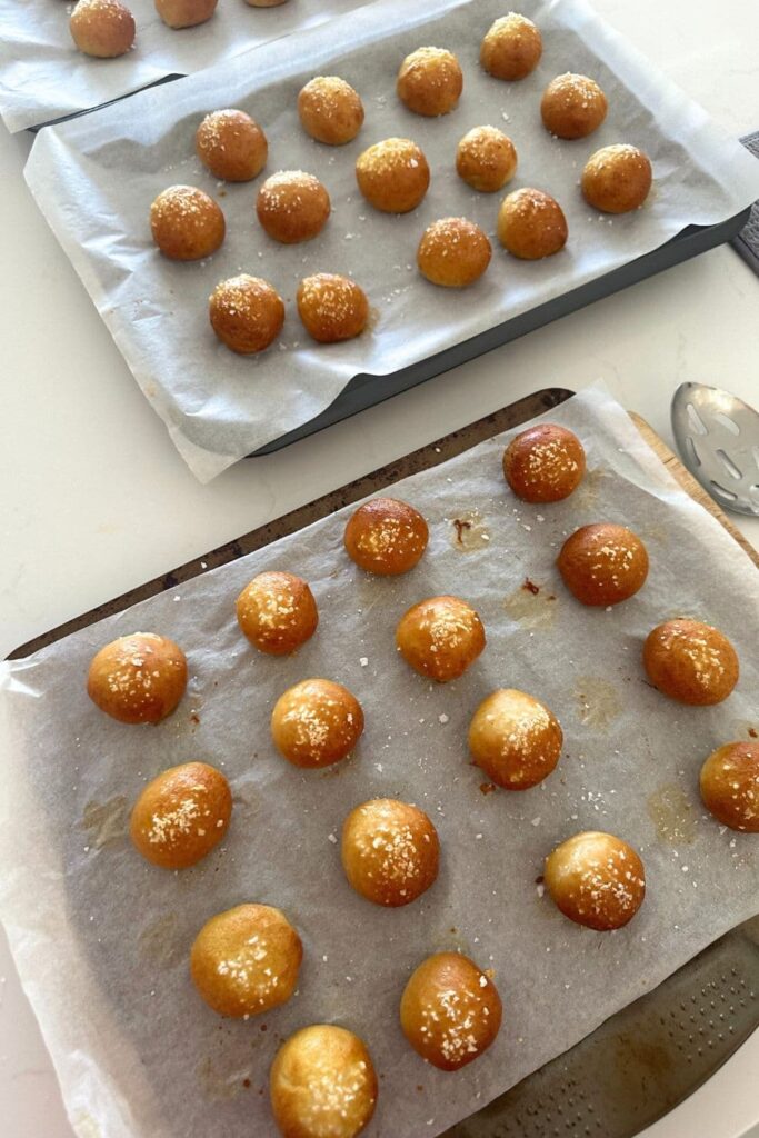 Freshly baked sourdough discard pretzel bites cooling on baking trays.