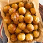 An enamel tray filled with sourdough discard pretzel bites. You can see a blue linen dish towel laying beside the tray.