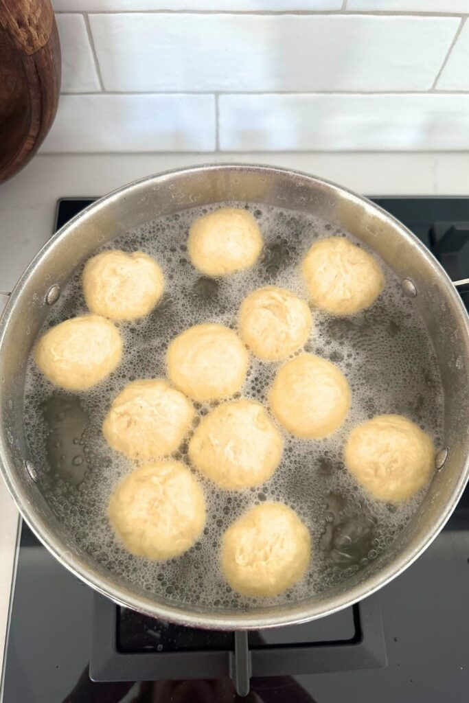 Sourdough discard pretzel bites being boiled in a large pot of water with baking soda to set the crust.