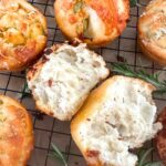 Sourdough focaccia bread muffins arranged on a black wire cooling rack.