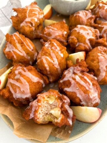 A platter of sourdough apple fritters topped with vanilla glaze.