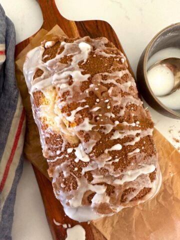 A loaf of sourdough discard cinnamon ripple quick bread on a wooden serving platter.