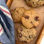 Spiced pecan sourdough cookies laid out on a rattan tray. There is a also a blue and red striped dish towel in the photo.