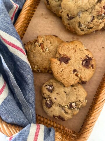 Spiced pecan sourdough cookies laid out on a rattan tray. There is a also a blue and red striped dish towel in the photo.