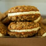 A close up of 2 sourdough oatmeal cream pies filled with vanilla cream filling.