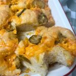A red borded cream enamel baking dish filled with sourdough dill pickle cheddar focaccia bread.