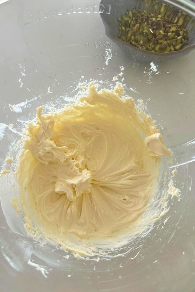 Mixing cream cheese in glass bowl for honey pistachio cream cheese recipe.