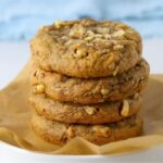 Sourdough date and walnut cookies stacked on a parchment paper lined plate.