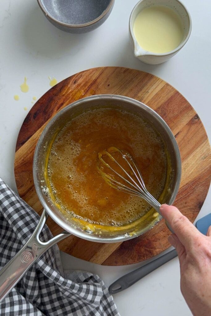 A saucepan of melted sugar that has had some butter added to it and it has foamed up. 