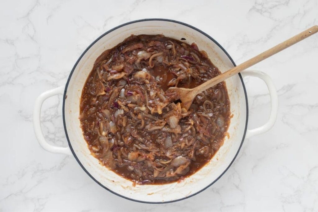 Showing all ingredients in a pot, cooking to make caramelized onion relish.