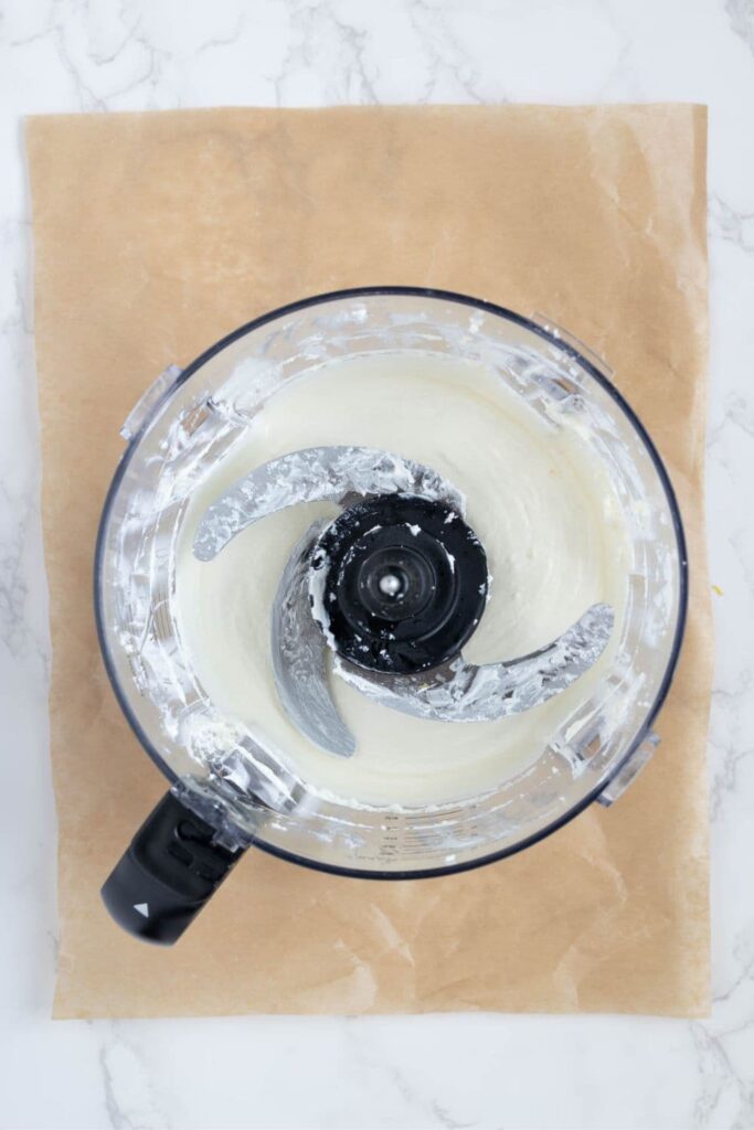 Smooth whipped feta dip inside the bowl of a food processor.