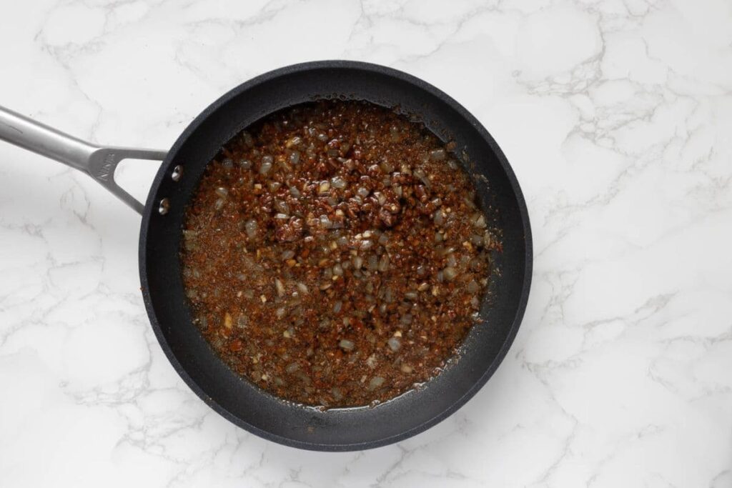 Adding coffee, brown sugar, apple cider vinegar, and maple syrup to a pan to make bacon jam.
