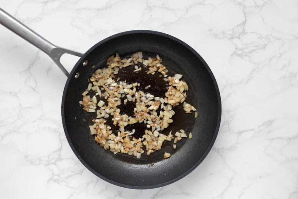 Sautéing onions in a pan to make bacon jam.