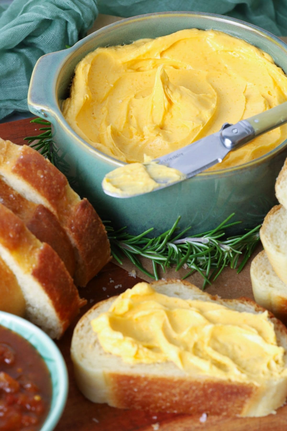 Slice of sourdough bread with cheddar butter spread on top from the serving bowl of cheddar butter.