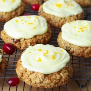 Close up of orange cranberry sourdough oatmeal cookies with orange butter glaze on a cooling rack.