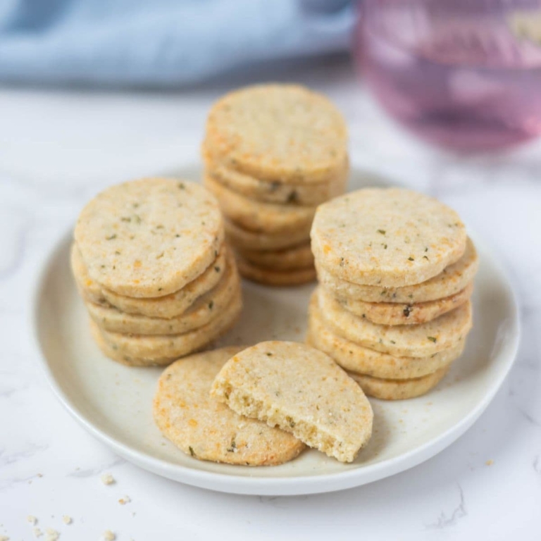 Close up of stacked sourdough discard rosemary and parmesan shortbread on a serving plate.
