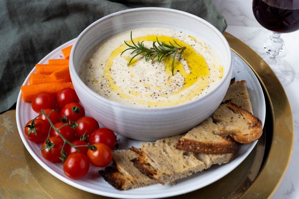 White bean dip on a serving platter with vegetables and sourdough toast.